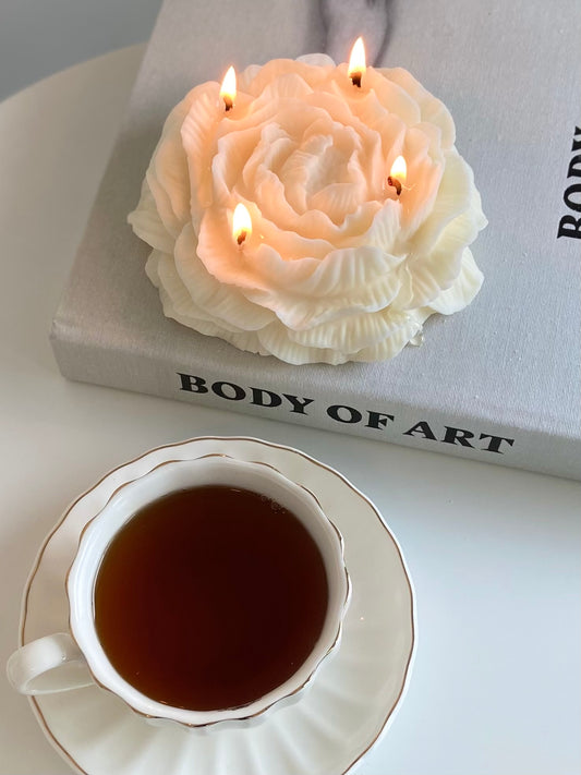 large peony shaped candle with a cup of coffee on a "body of art" book